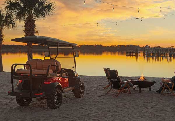 Voiturette de golf rouge soulevée - Scène de plage avec feu de camp